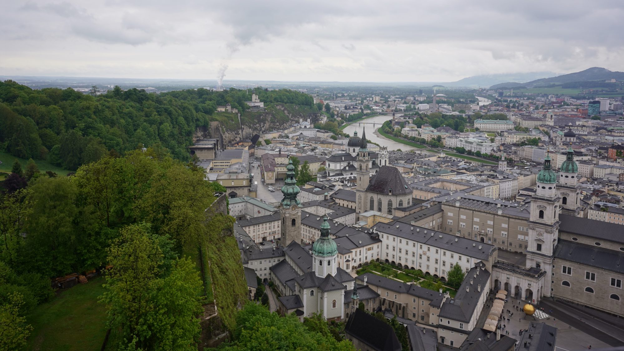 Salzburg from above; green hills to the left, low buildings and a curvy river to the right