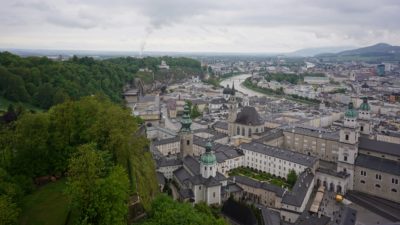 Salzburg from above; green hills to the left, low buildings and a curvy river to the right