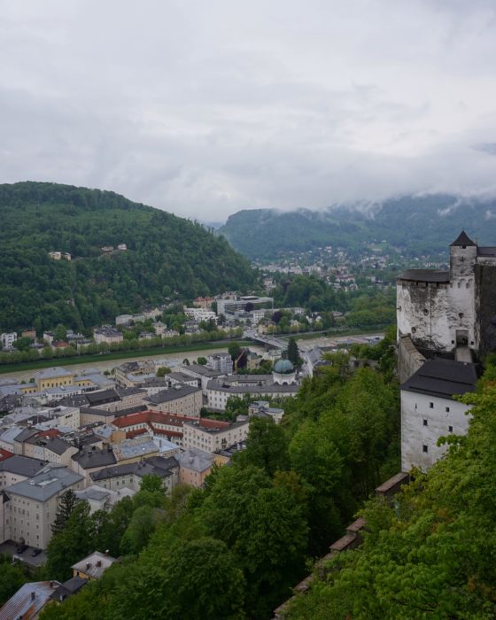 Looking down at Salzburg; a fortress tower to the right, the river and a bridge, and more green hills