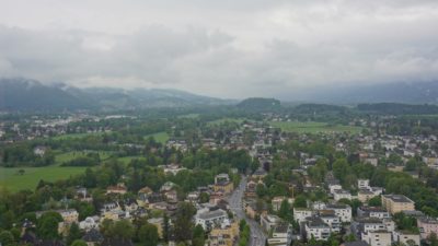 Some scattered houses, green landscape and hills under a grey sky