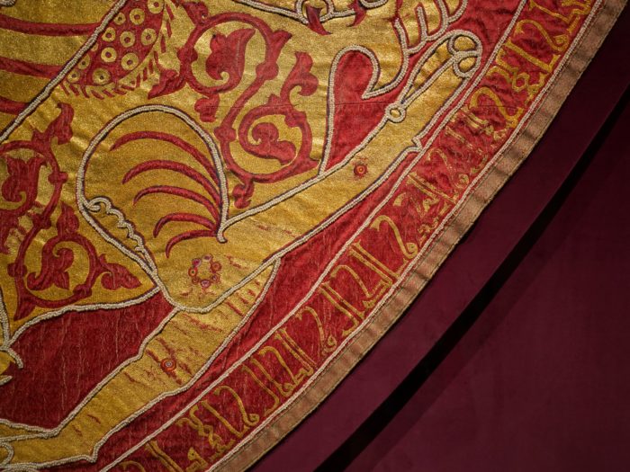 Closeup of a semi-circular mantle, richly decorated in red and gold