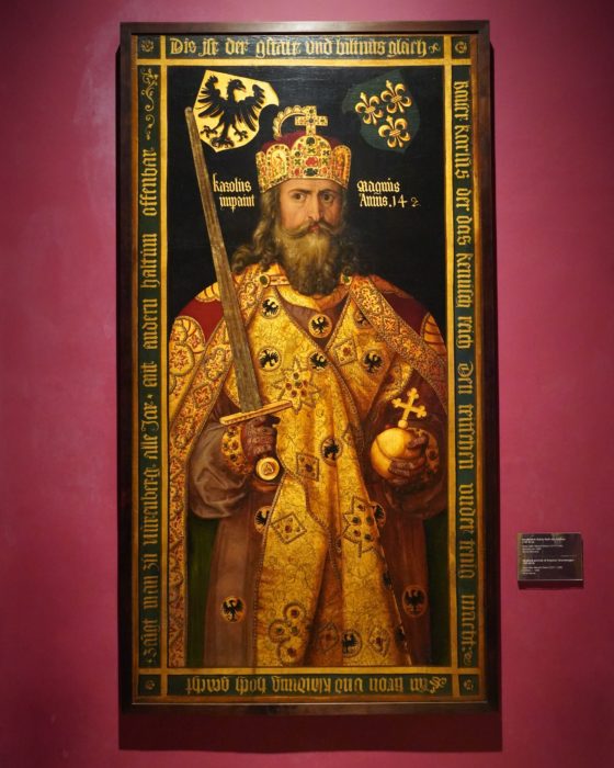 A painting of Charlemagne, upright and holding a sword in one hand and an imperial orb in the other