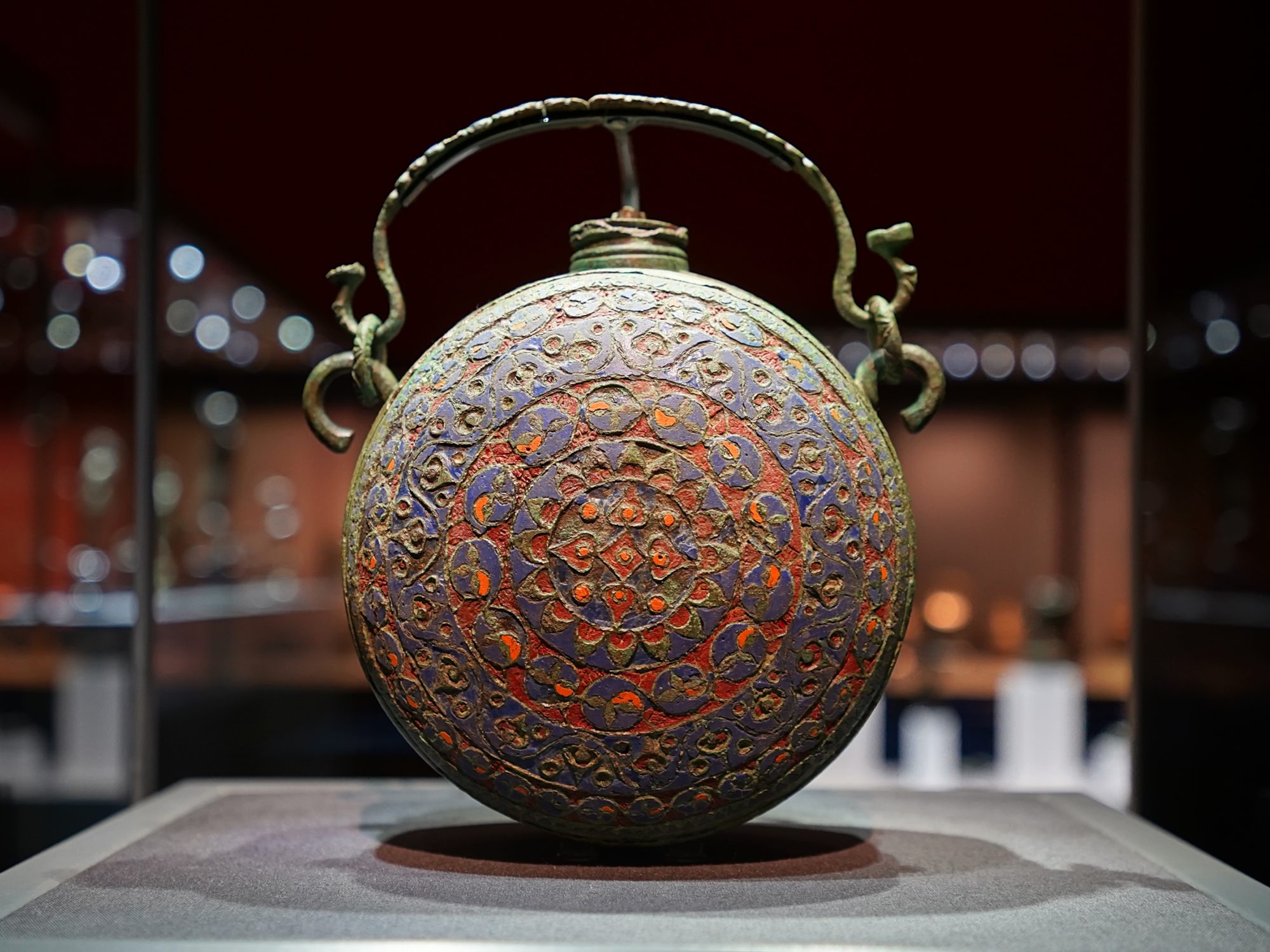 A circular bronze purse with swirly red and purple patterns