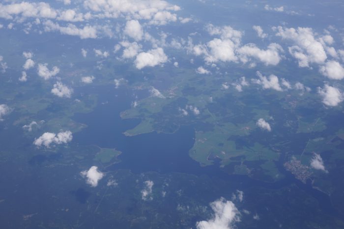 A jagged lake seen from a plane. There are some clouds above the ground