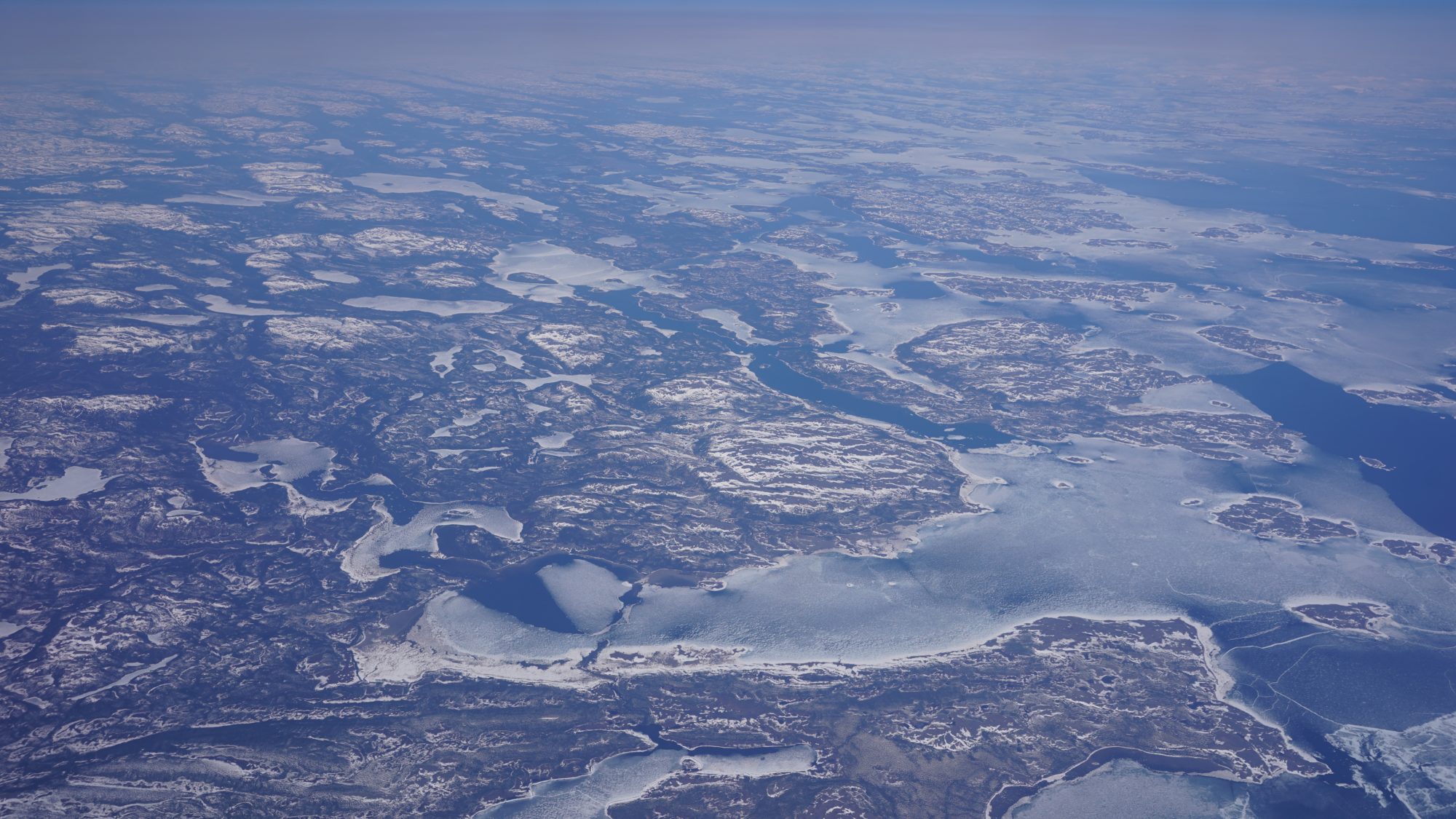 A rough coastline with many deep inlets and small islands, all cold and barren and dusted with snow