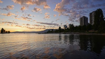 The West End towers and Sunset Beach seen from the ferry dock. The sun has gone down, and there are little choppy clouds in the sky, coloured orange-pink