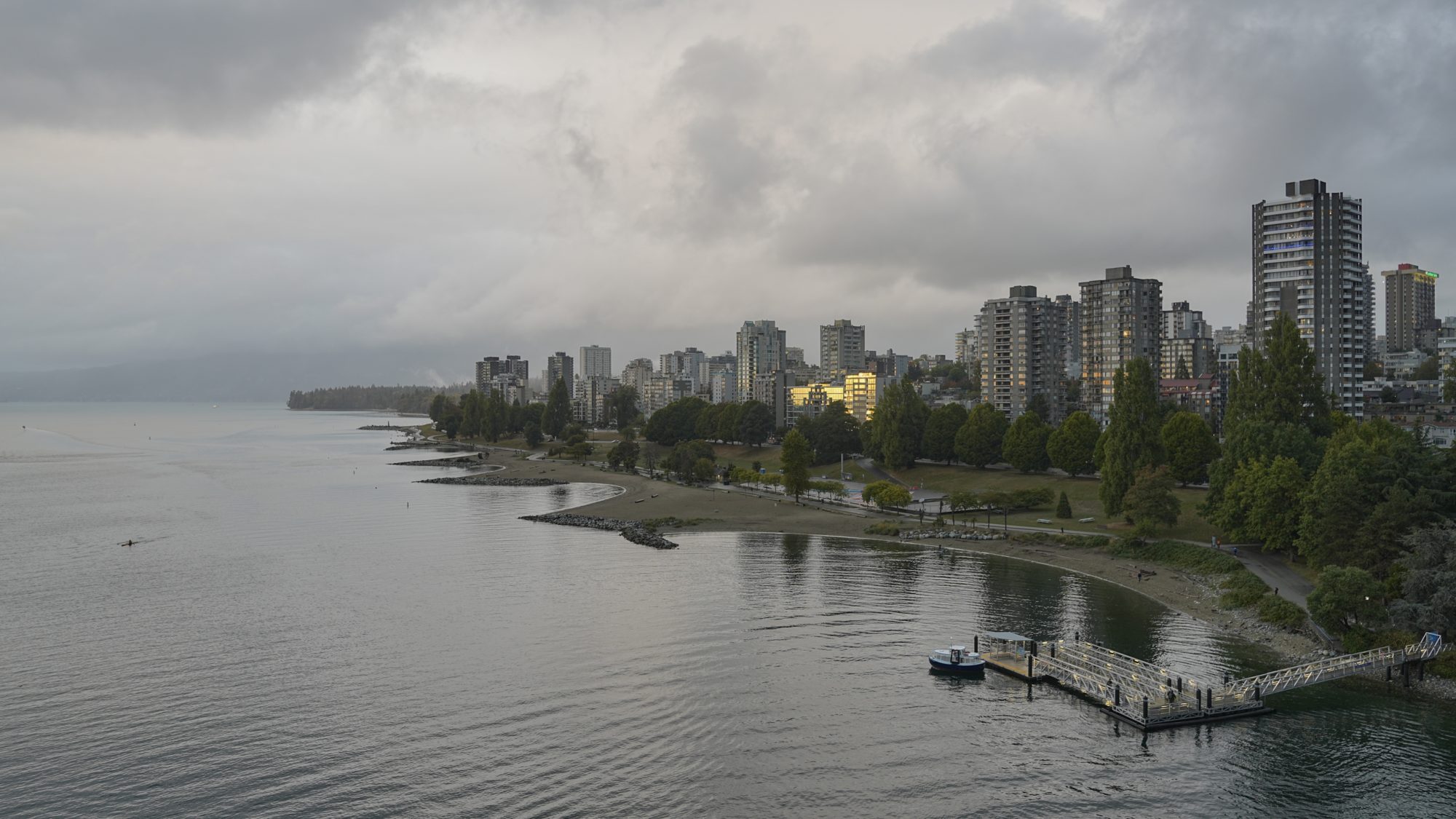 Sunset Beach and West End towers. The sky is grey, and one single building is reflecting gold light from the sunset