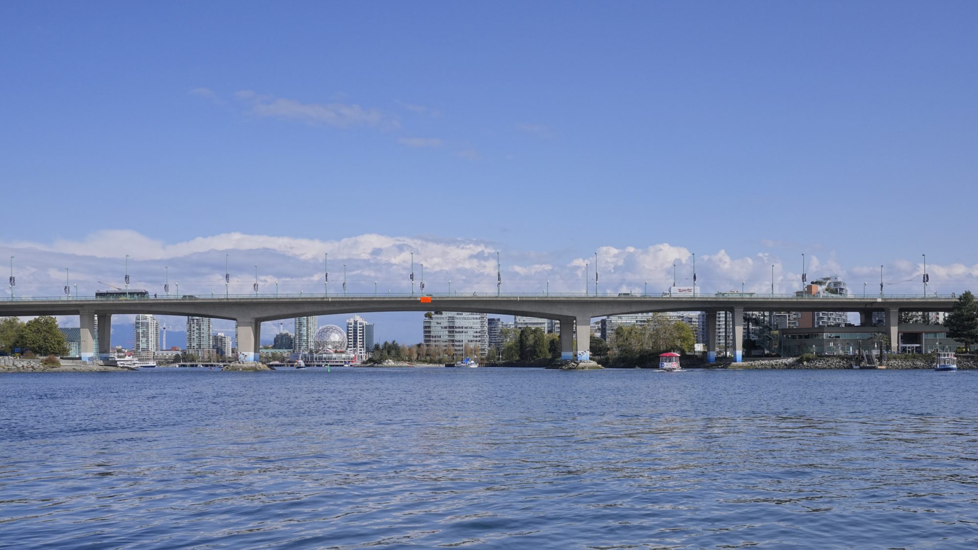 A view of Cambie Bridge from the marina at the foot of Davie Street. The water is clear and the sky is blue