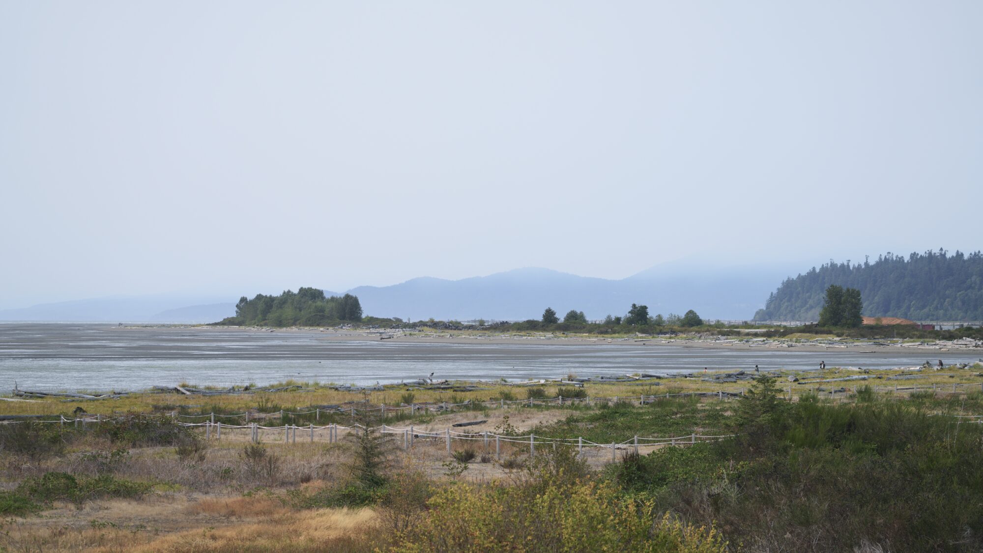 View of the Iona Beach north jetty, with hazy mountains in the background